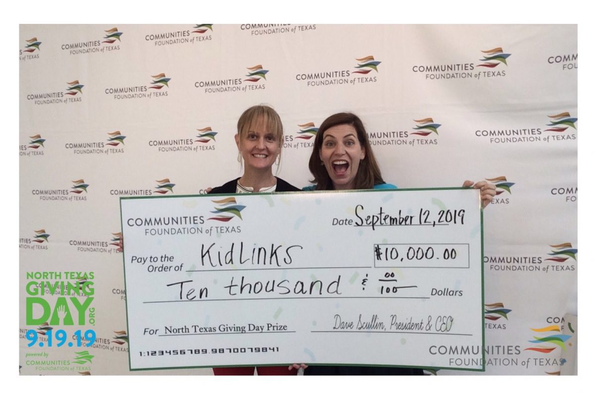 Two women hold a large check made out to KidLinks for $10,000